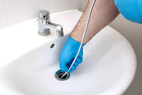 A drain being cleaned in a bathroom sink